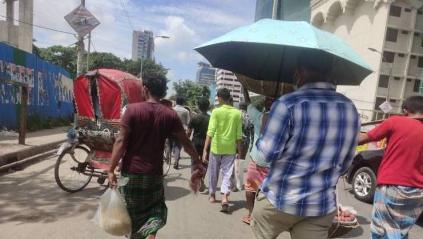 অসহনীয় গরমে রোদের তীব্রতা থেকে রক্ষা পেতে  ছাতাটি মেলে ধরেছেন পথচারী। ( ছবি : সুলতানা আক্তার )